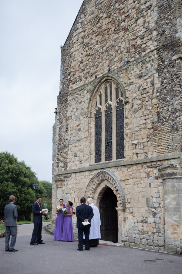 bridesmaids and vicar in front of church